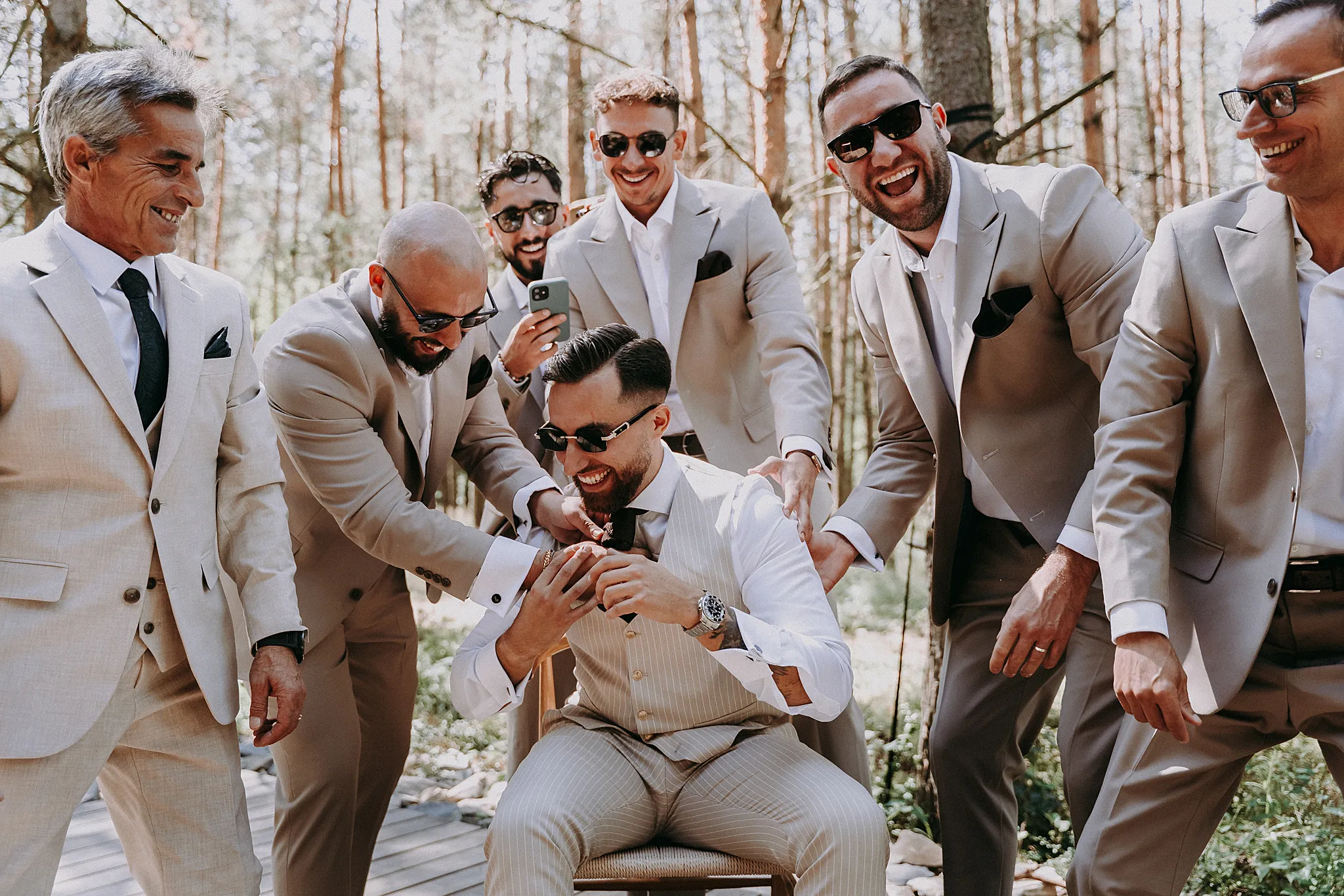 Pan młody z drużbami przed wejściem do drewnianego domku w lesie w okolicach pszczyny